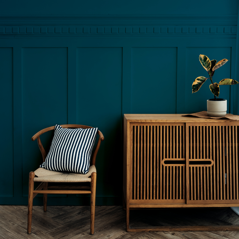 scandinavian vintage wood cabinet with chair by dark blue wall